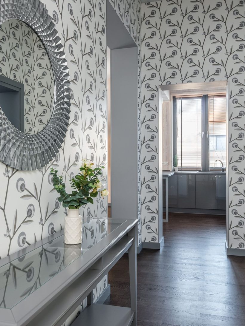 Hallway with soft sage botanical wallpaper, a round mirror, and a console table