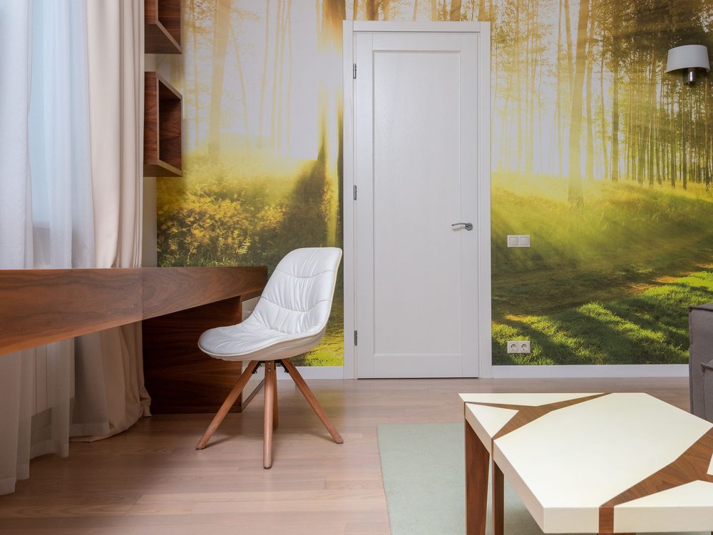 Home office with a forest mural wallpaper, a writing desk, and a modern chair