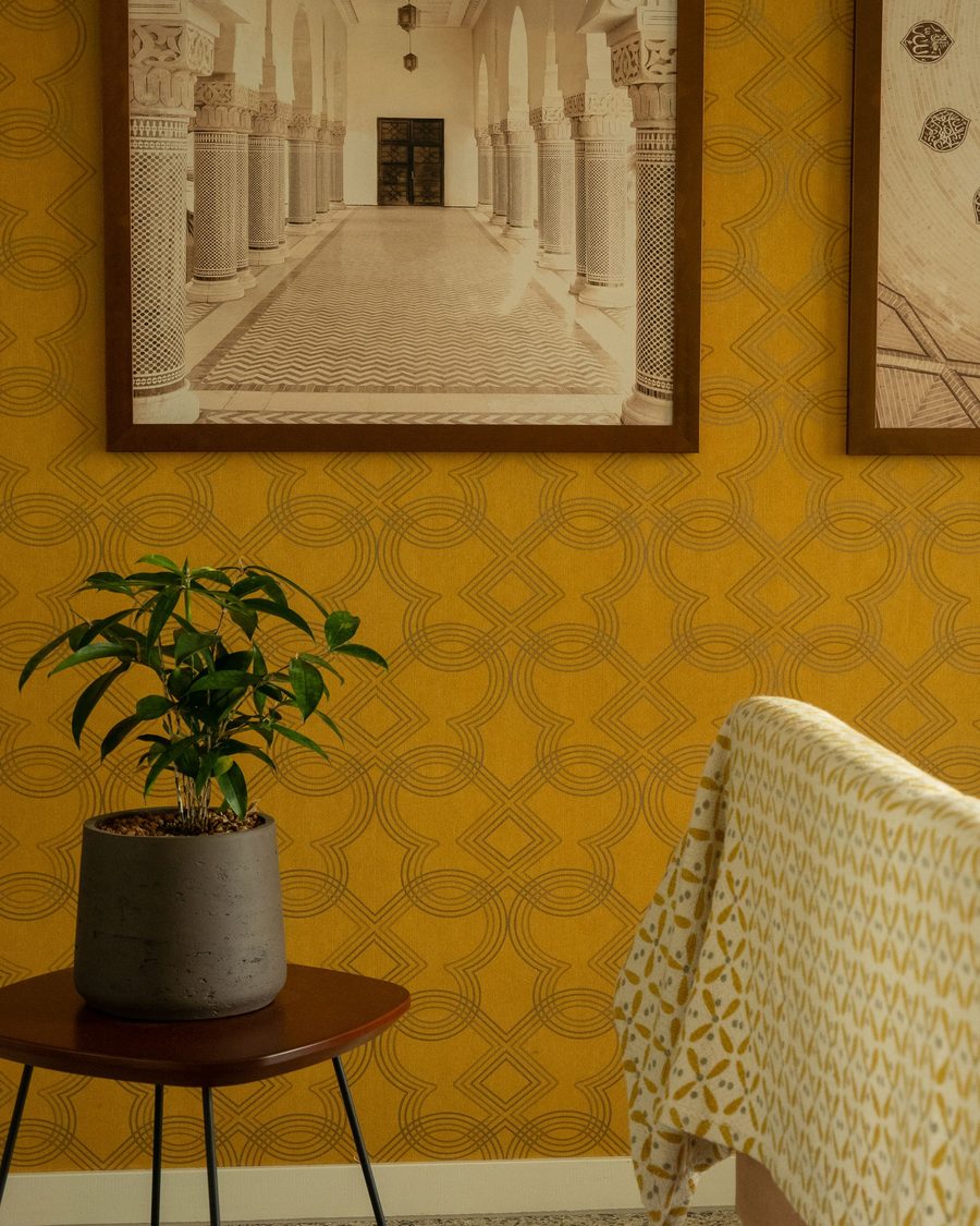 Warm ochre accent wall with framed architectural artwork and a potted plant
